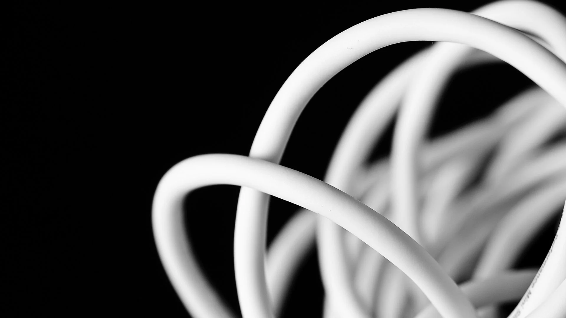 Close-up of Tangled White Cables Against a Black Background, Representing Comdiel's Connectivity Solutions.