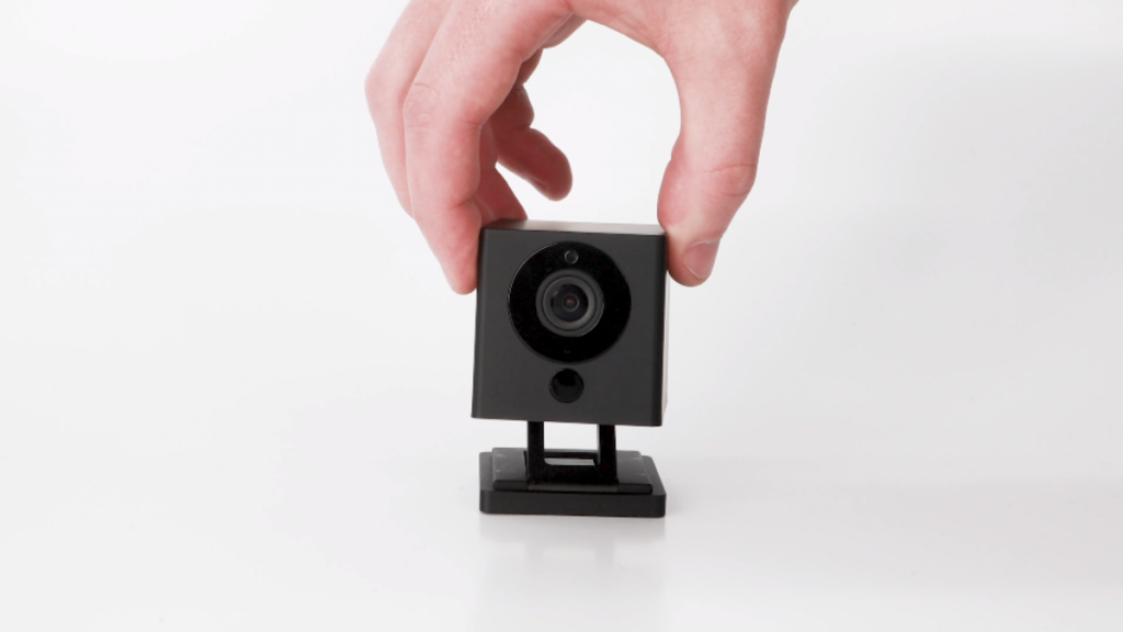 Wyze-7 | Atwix Hand Adjusting a Black Wyze Security Camera on a White Background.